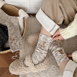 Detail of warm brown knit socks featuring a delicate cartoon bear embroidery craft