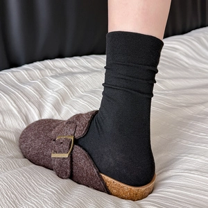 Close-up of brown wool felt clogs with cork soles and black ribbed crew socks