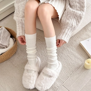 Detailaufnahme der cremeweißen Wollsocken mit vertikaler Rippenstruktur und Faltenwurf