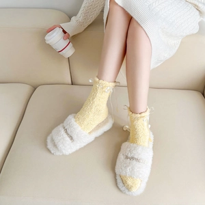 Vue détaillée de chaussettes en molleton corail jaune avec nœuds et chaussons en peluche
