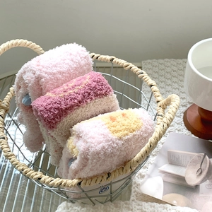 Detailed view of thick coral fleece socks in three soft pastel colors within a metal basket