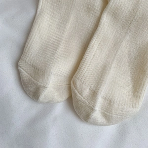 Close-up of cream white ribbed wool tights showing toe seam detail and knit texture