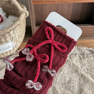 Detailed close-up of knit leg warmers with ribbon bow and cherry charm accents