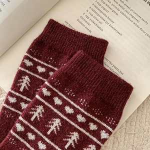 Detail of burgundy wool socks with white jacquard heart and Christmas tree patterns