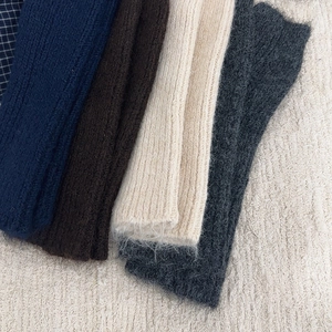 Close-up of knit leg warmers in navy, coffee, beige, and dark grey soft mohair texture