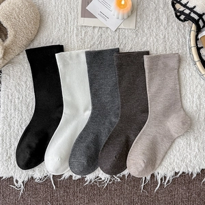 5-pack of minimalist solid cotton crew socks in earth tones on a soft white rug