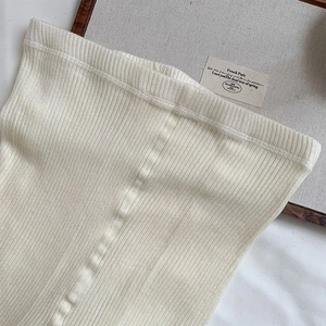 Close-up detail of off-white wool leggings featuring a ribbed knit texture and elastic waist