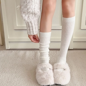 Weiße Wollsocken mit Rippenmuster und flauschige Hausschuhe für gemütliche Tage