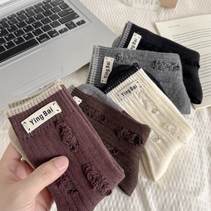 Detail view of distressed knit wool socks with white cloth labels and ribbed texture