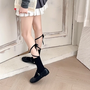 Detail of black ballet-style knee-high socks with criss-cross satin ribbons and bows