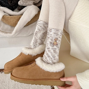 Detail of warm brown suede slippers with white plush lining and bear embroidery socks
