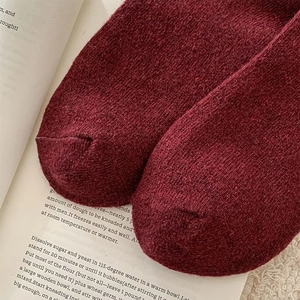 Close-up of seamless toe stitching on dark red knitted wool socks with textured fabric