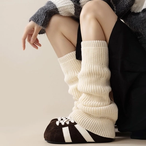 Detailed view of cream vertical knit leg warmers paired with retro brown sneakers