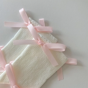Detailed macro view of white cable knit leg warmers with sweet pink satin ribbons