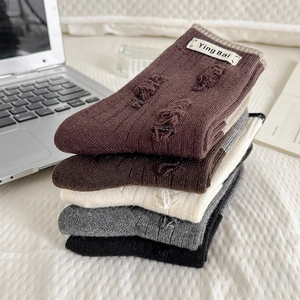 Detailed view of five vintage ribbed wool socks with distressed holes and woven labels