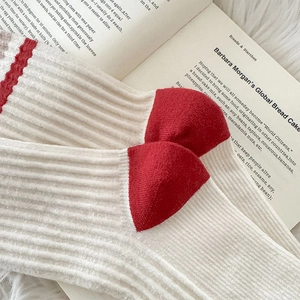 Detail of white ribbed crew socks with red heel and wavy edges on a book background
