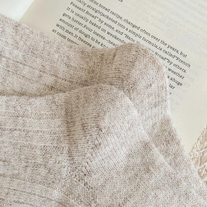 Close-up of oatmeal beige cable knit texture on warm winter socks with book background