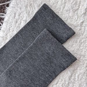 Close-up of dark grey ribbed knit fabric texture on soft white fleece background