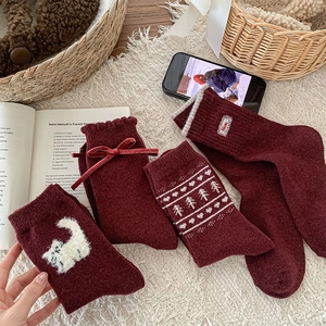 Detail of red wool socks featuring velvet bow, cat embroidery, and Nordic patterns