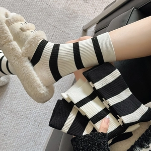 Detailed close-up of black and white striped ribbed knit socks worn with plush slippers
