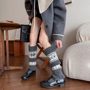 Detailed close-up of knitted leg warmers with grey ethnic snowflake patterns and rib cuffs