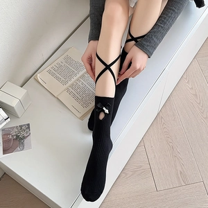 Detail of black calf socks with cross straps, bow and pearl accents in Lolita style