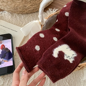 Detail of burgundy wool socks with white polka dots and cat pattern in a basket