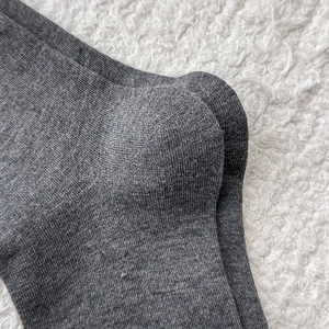 Close-up of dark grey knitted sock heel showing fine texture on a white plush rug