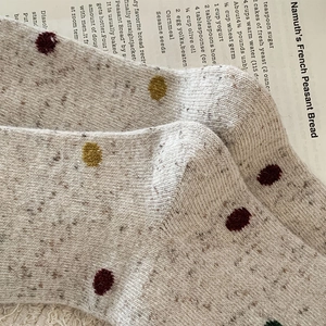 Gros plan de chaussettes en laine grise à pois colorés sur un fond en papier vintage