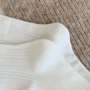 Macro view of white vertical ribbed knit fabric with delicate wave texture for socks