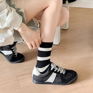 Detail of ribbed black and white striped socks paired with retro contrast sneakers