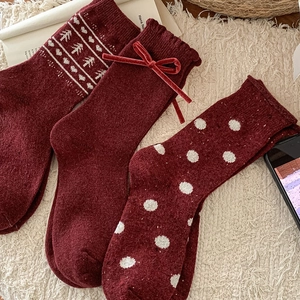 Detailed view of three dark red knit wool socks with velvet bow and polka dot patterns