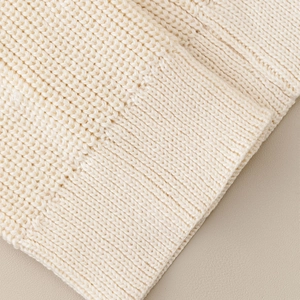 Detailed macro view of the thick vertical ribbed knit texture on cream leg warmers
