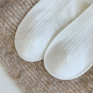 Close-up of white ribbed crew socks showcasing fine knitting patterns and soft texture