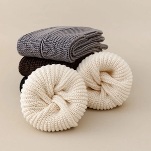Detailed close-up of ribbed knit leg warmers in cream, grey, brown and black colors