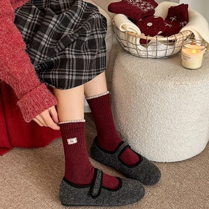Close-up of deep red wool socks with ribbed cuffs and grey Mary Jane shoes in a winter setting