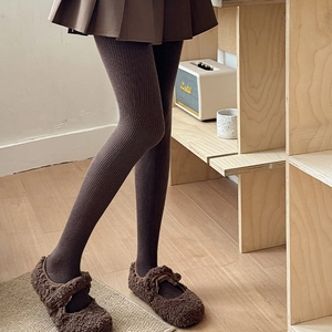 Detail of dark brown vertical stripe thermal leggings paired with a pleated skirt