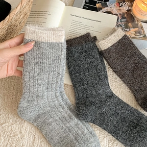 Close-up of thick knitted wool socks with contrast cuffs on a cozy textured background