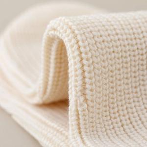 Close-up of white ribbed knit fabric showing soft texture and premium vertical stitching