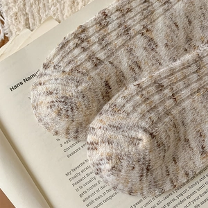 Close-up of thick beige and brown knit texture of cartoon bear warm winter socks