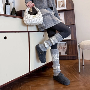 Detail of grey wool knit leg warmers with Nordic snowflake pattern and felt clogs