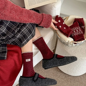 Detail of red wool socks with lace tag and ribbed cuffs paired with Mary Jane shoes