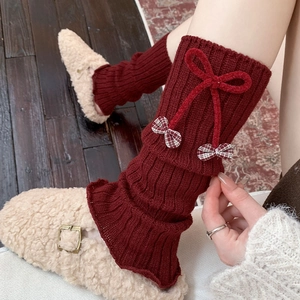 Close-up of red knit leg warmers with velvet bows and a vintage balletcore aesthetic