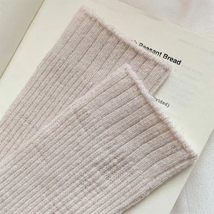 Detailed macro view of cream-white vertical ribbed knit wool socks with soft texture