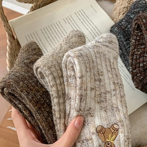 Close-up of thick knit socks in a basket featuring a detailed bear embroidery detail