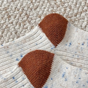 Close-up of thick vintage wool socks featuring colorful speckles and contrast heel stitching