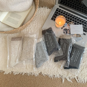 Set of five warm knitted wool socks in neutral tones with stylish branded packaging