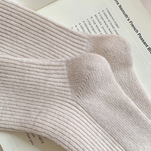 Macro shot of ribbed texture on cream-colored wool socks showcasing thick knitted detail