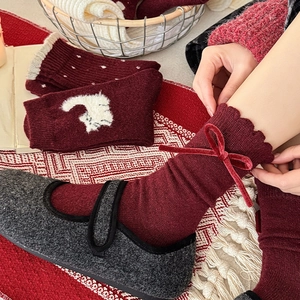 Detail of wool socks featuring red velvet bow decorations and wave-edged knit cuffs