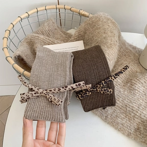 Detail view of ribbed knit crew socks featuring cute leopard print bow ribbon accents